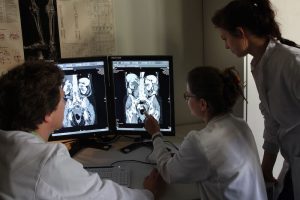 Drei Mediziner betrachten ein Ultraschallbild an zwei Bildschirmen. Beitragsbild zum Artikel Rezidivierendes gynäkologisches Karzinom - Wie geht es weiter?