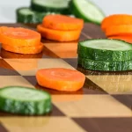 Photo for the article "A balanced diet". Cucumber and beet slices on a chess board.